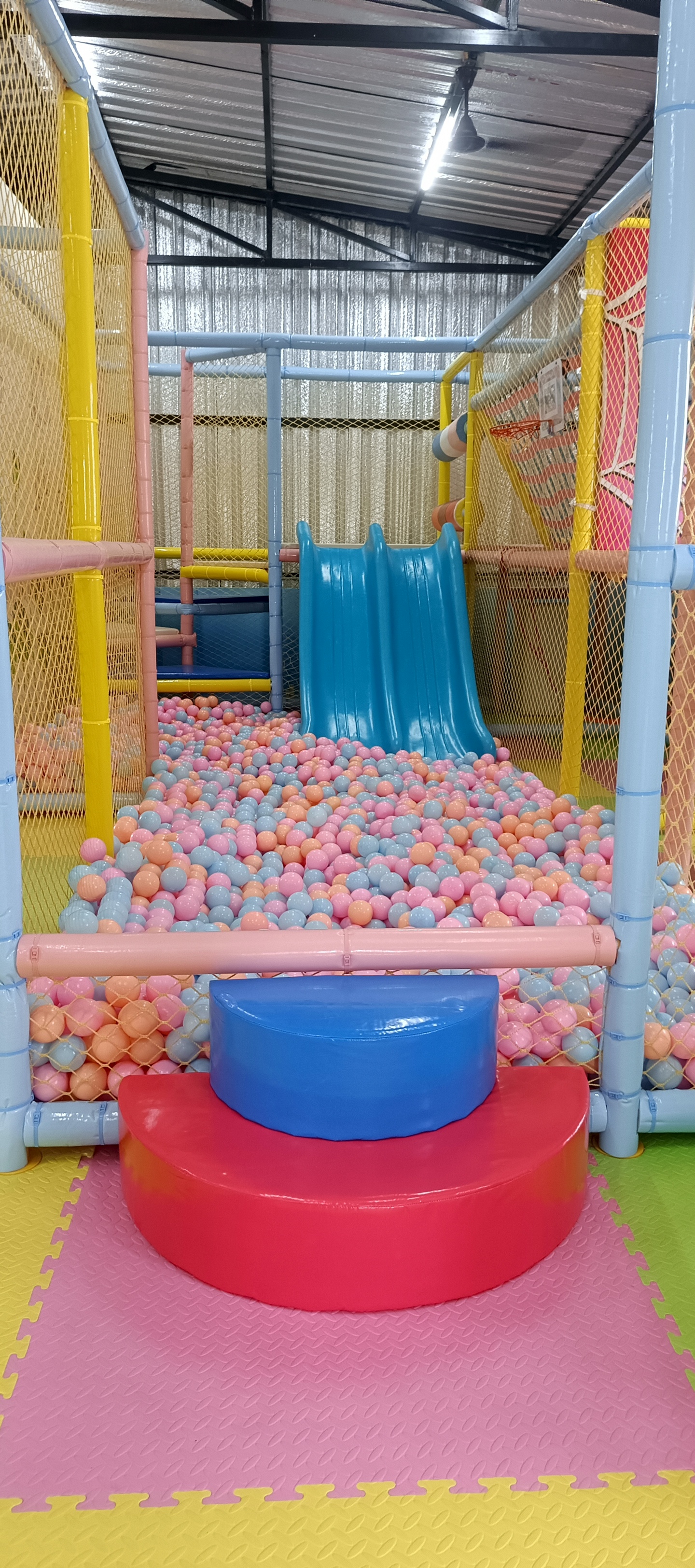 Indoor playground structure with climbing frames, soft play and bright colourful netting