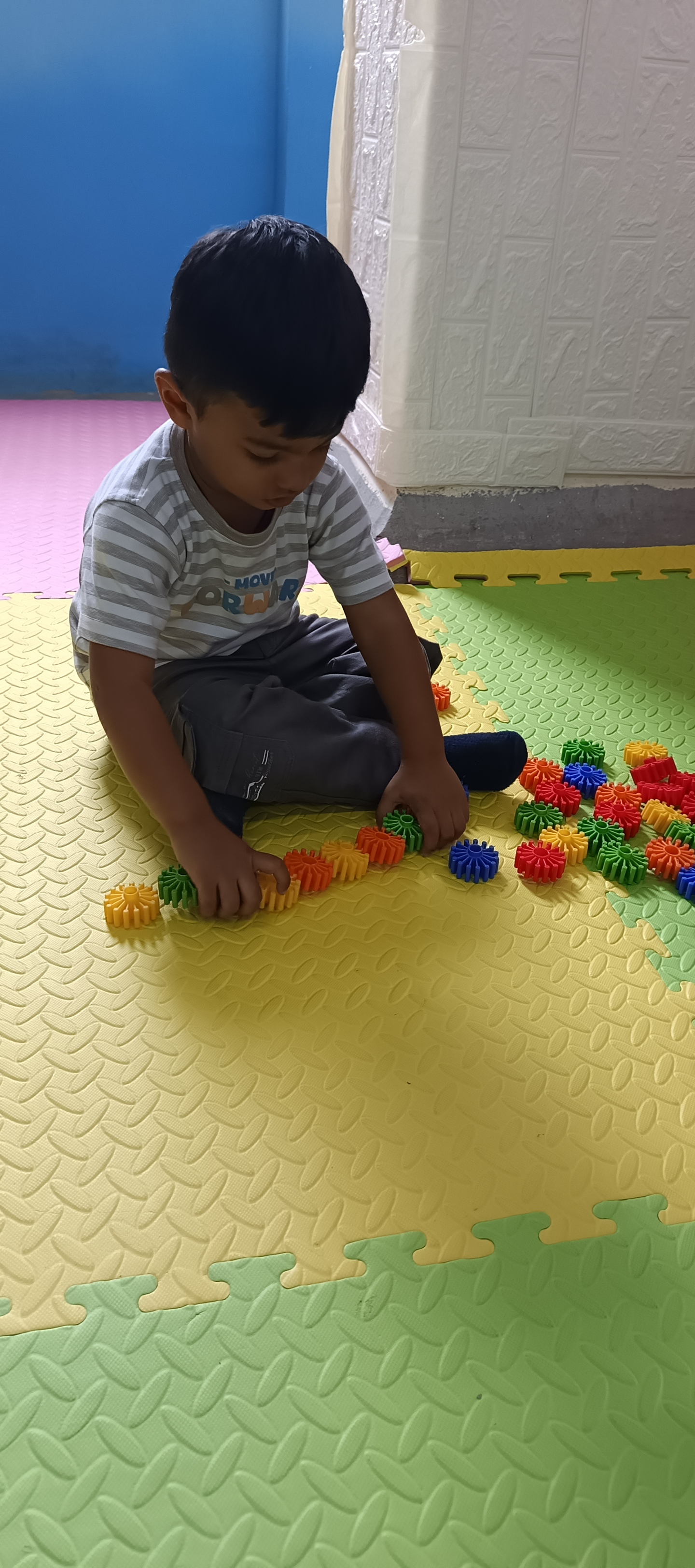 Child connecting colorful puzzle gears on activity mat