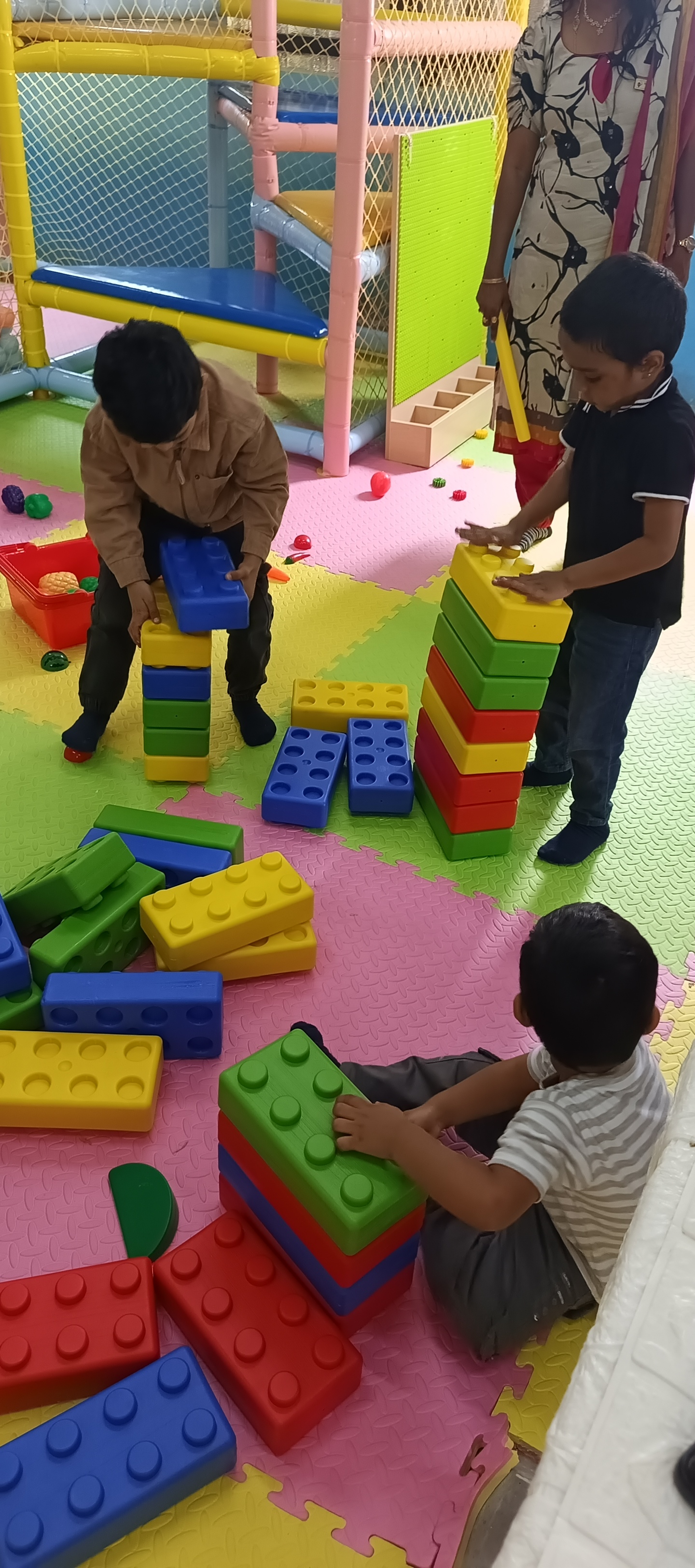 Students building block towers with teacher supervision